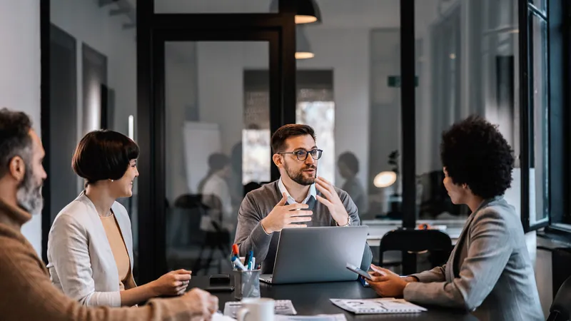 A business coach talking with three owners around a conference table