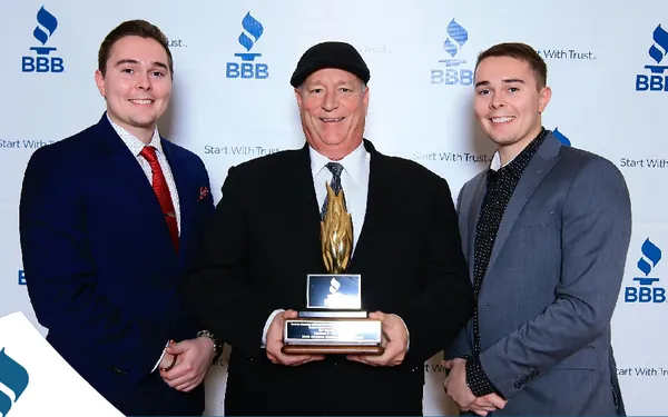 Tim Willson holding a BBB Torch Award for Marketplace Ethics, standing between his sons Luke and TJ